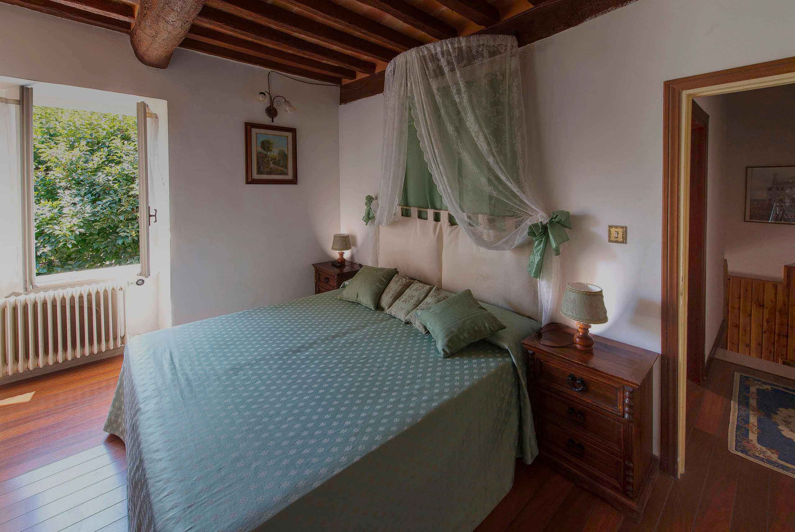 Camera matrimoniale con parquet e copriletto verde ulivo